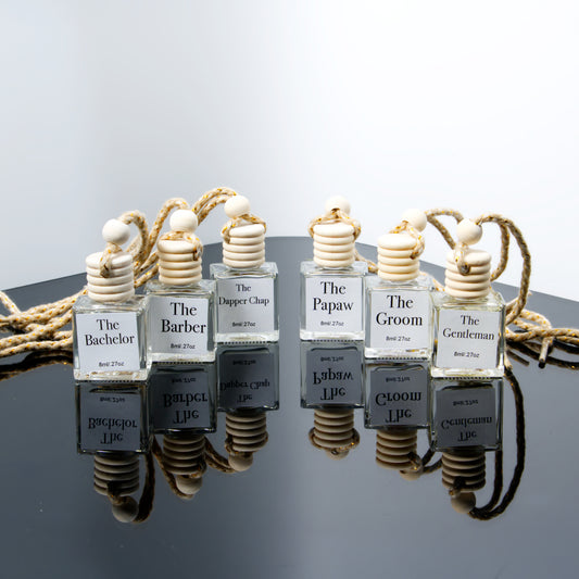 Set of hanging air diffuser bottles labeled with names like 'The Bachelor', 'The Barber', and 'The Papaw' on a reflective surface.