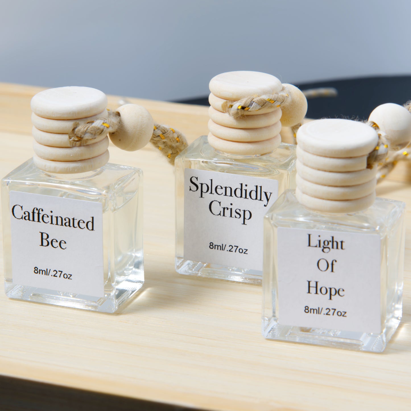 Three hanging air diffuser bottles with wooden caps on a wooden surface.