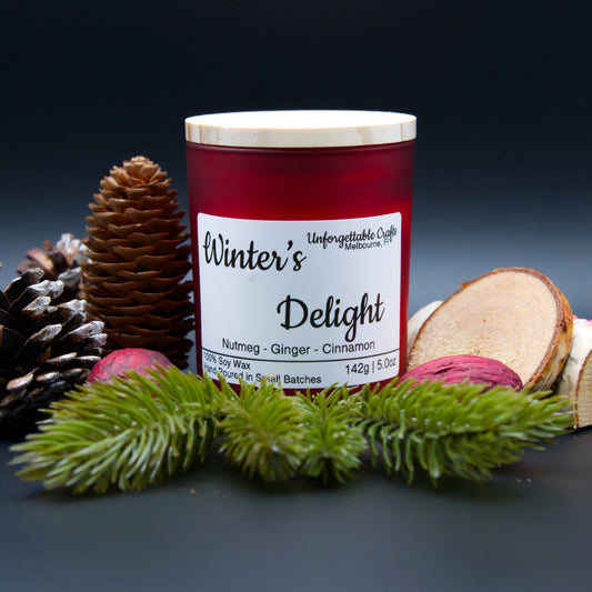 Candle labeled 'Winter's Delight' with decorative elements on a dark background