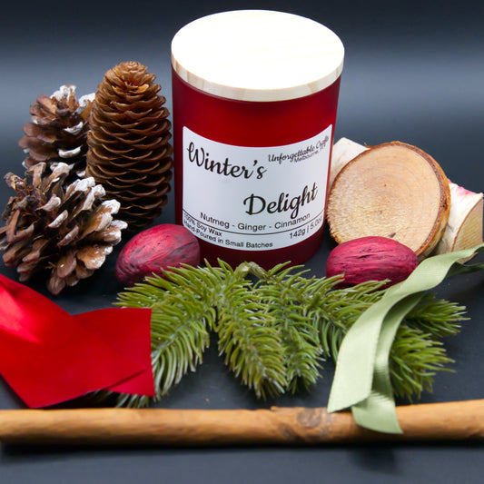 Candle labeled 'Winter's Delight' surrounded by decorative elements on a dark background
