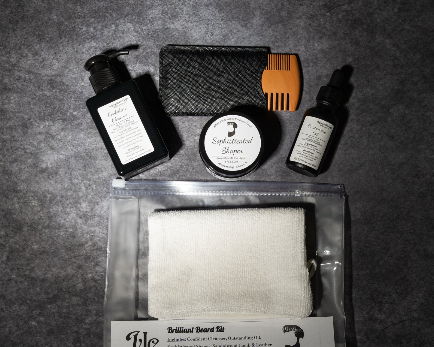 Collection of grooming products including a bottle, jar, and towel on a dark surface with 'UC' branding.