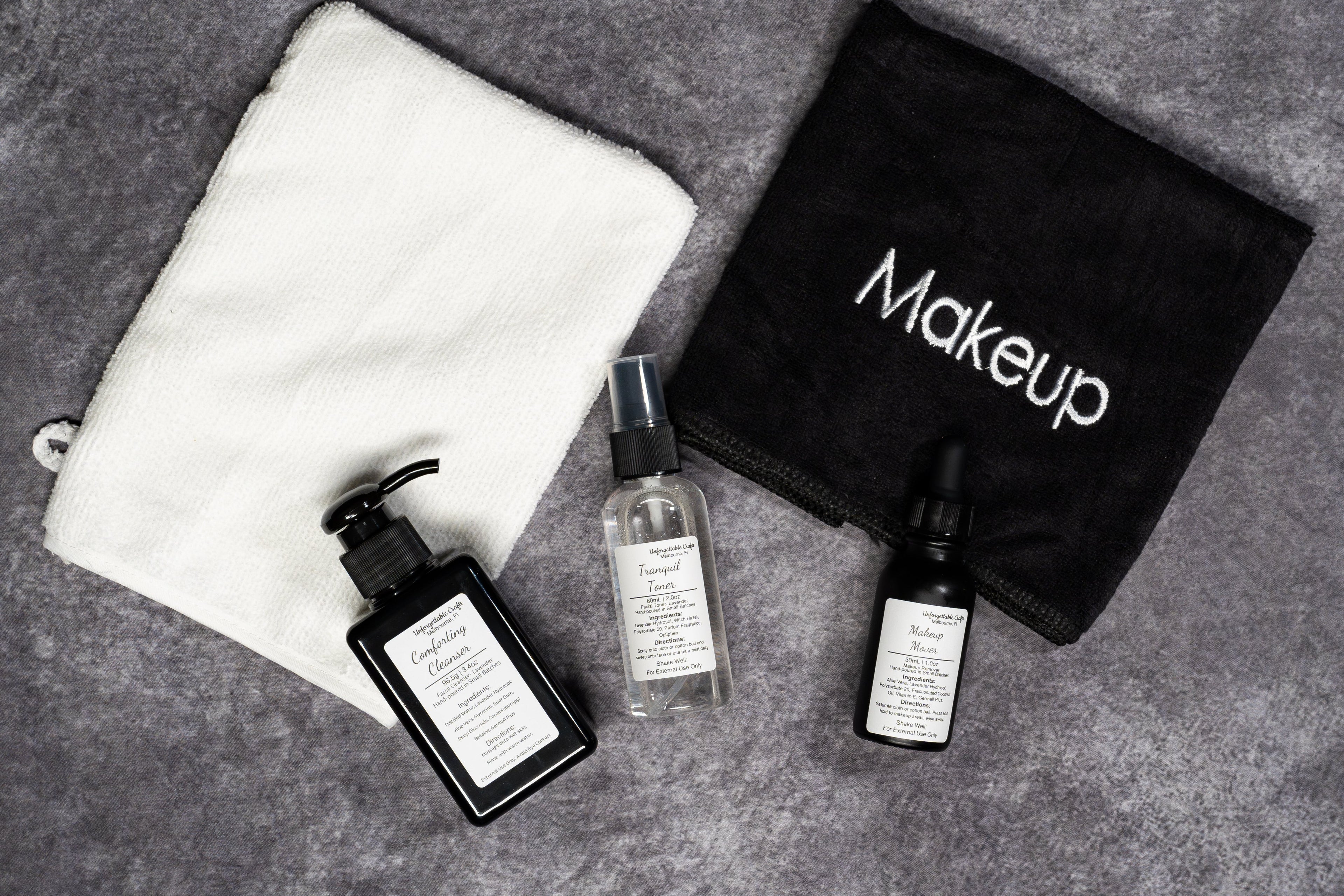 Facial Rejuvenating Kit and a black cloth labeled 'Makeup'  beside a white mitten cloth on a gray surface