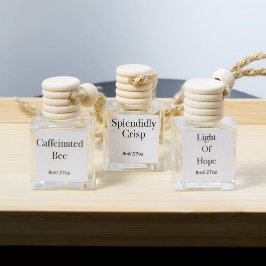Three hanging air diffusers glass bottles with labels on a wooden surface