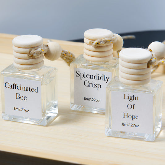 Three hanging air diffuser  bottles with wooden caps on a wooden surface.