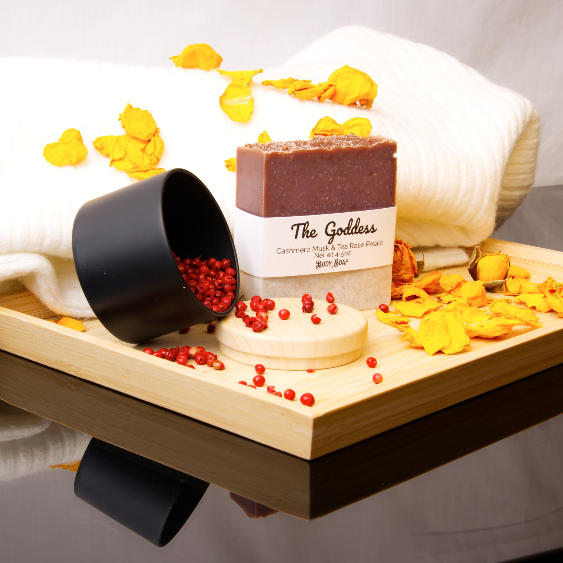 Bar of soap labeled 'The Goddess' on a wooden tray with decorative elements.