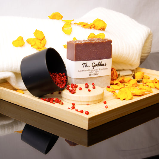 Bar of soap labeled 'The Goddess' on a wooden tray with decorative elements.