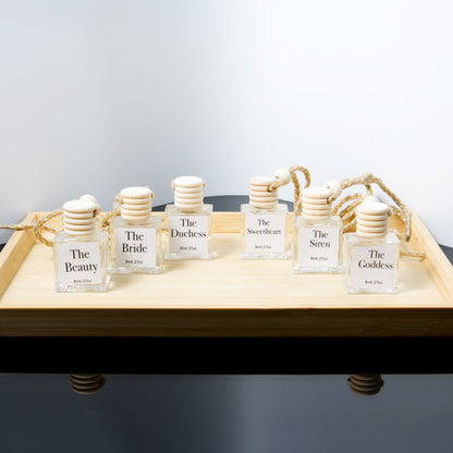Set of hanging air diffusers bottles labeled with names on a wooden tray.