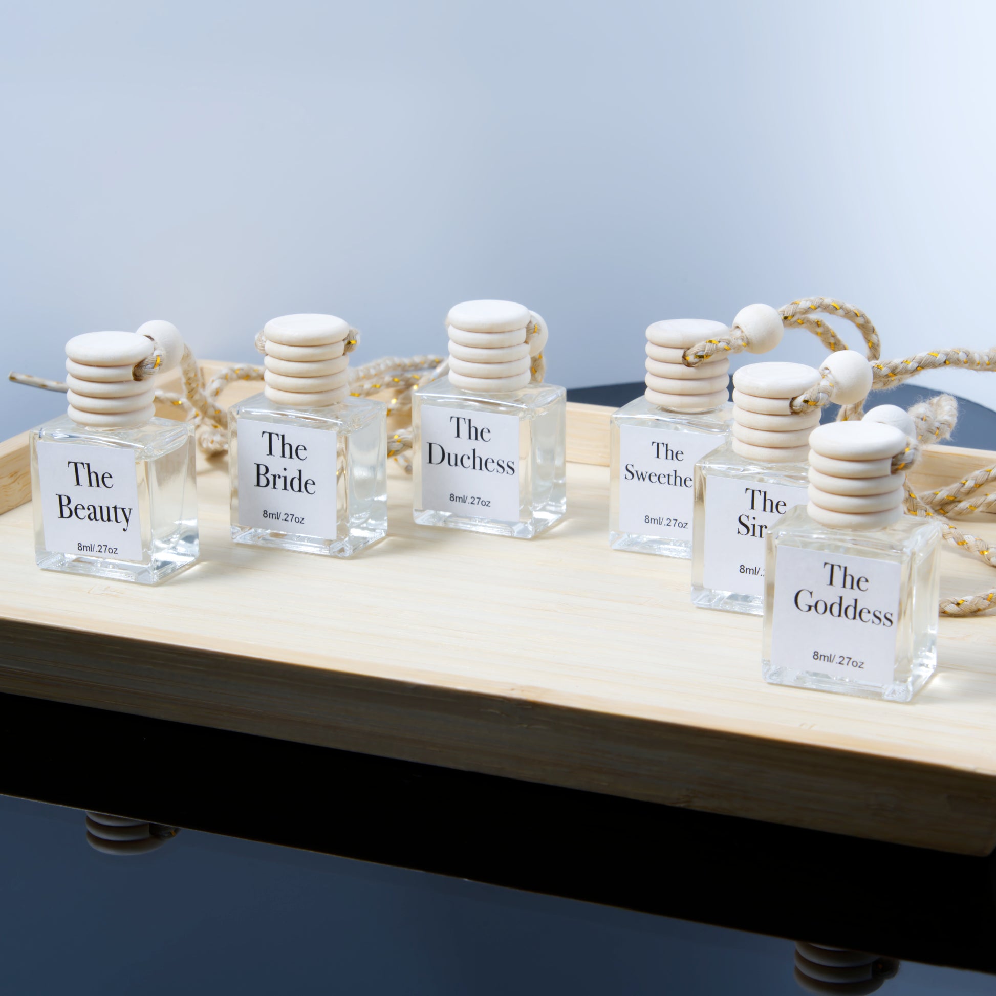 Set of hanging air diffuser glass bottles labeled with names on a wooden surface.